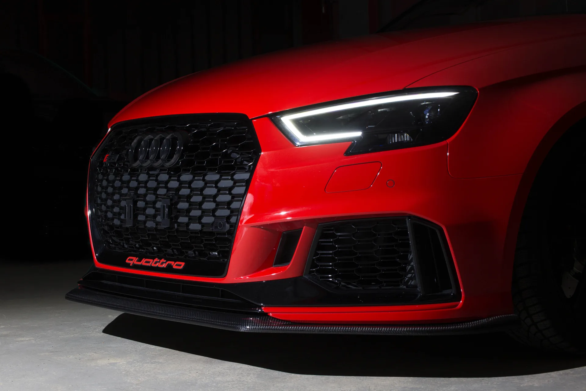 Roter Audi RS3 mit Carbon-Frontlippe im dunklen Showroom von MM Premium Cars