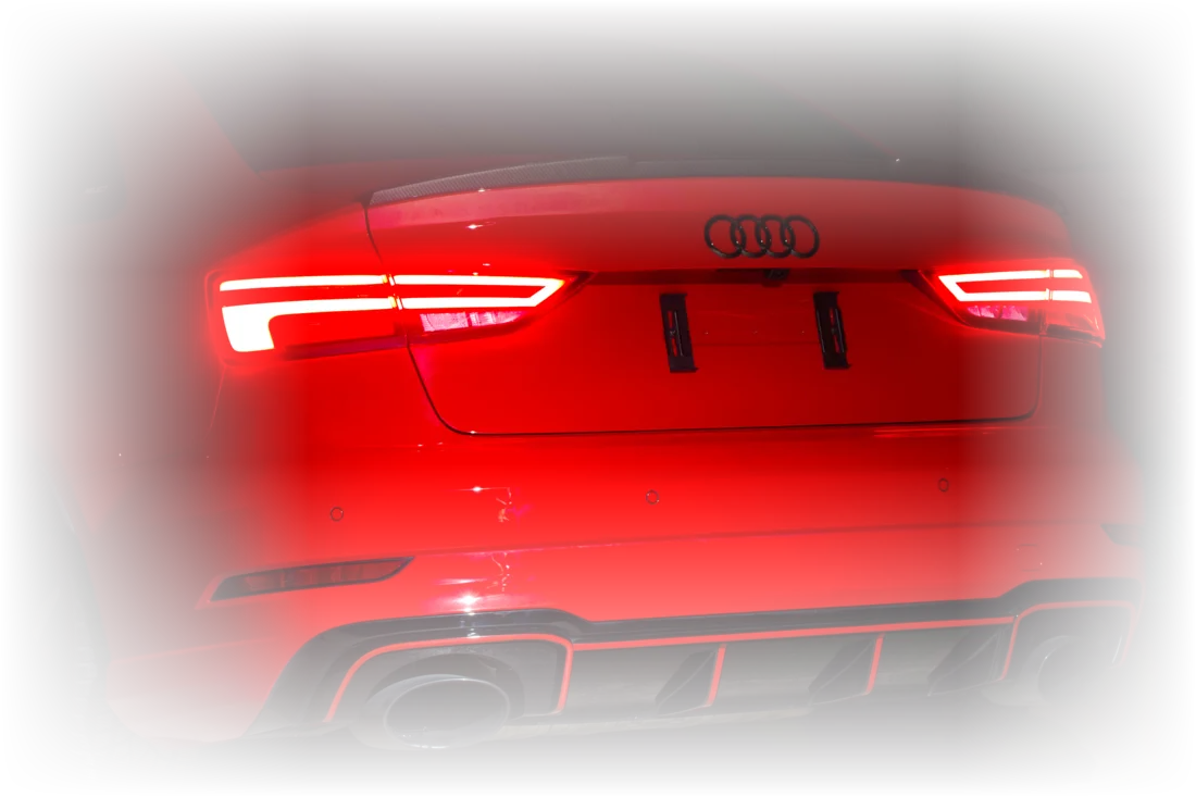 Glühende Heckleuchten des roten Audi RS3 im Dunkeln